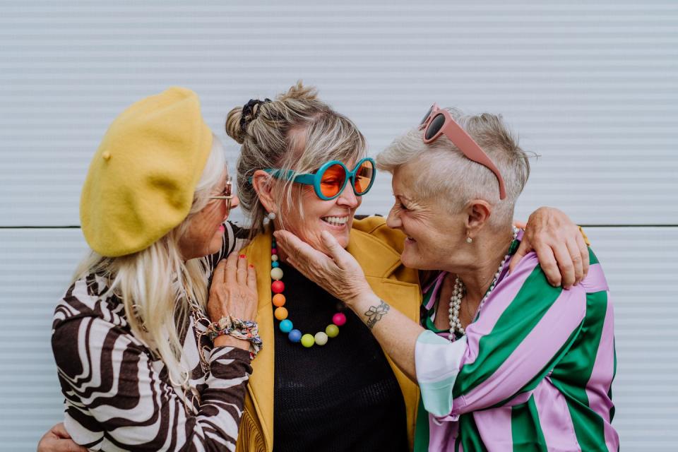 portrait of happy three senior friends in colourful clothes