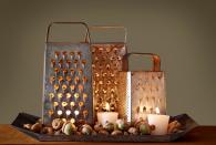 <p>Create moody ambience on a sideboard with this flickering display.</p><p><strong>Step 1: </strong>Arrange multiple vintage box graters (we found ours on Etsy) on a tray. Illuminate with flameless flickering LED votives to prevent the metal graters from becoming too hot to handle.</p><p><strong>Step 2: </strong>Fill in gaps on tray with acorns and extra candles. </p>