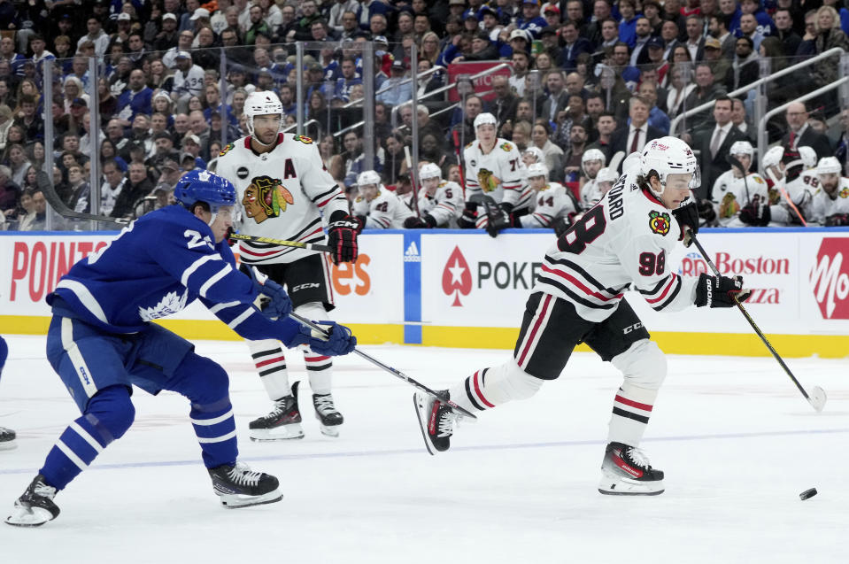 Toronto Maple Leafs left wing Matthew Knies, left, trips Chicago Blackhawks center Connor Bedard (98) during third-period NHL hockey game action in Toronto, Monday, Oct. 16, 2023. (Nathan Denette/The Canadian Press via AP)