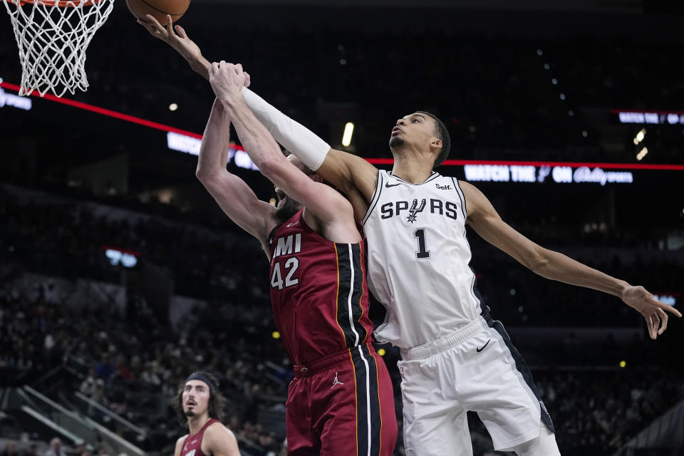 San Antonio Spurs center Victor Wembanyama (1) reaches over Miami Heat forward Kevin Love (42) for a rebound during the second half of an NBA basketball game in San Antonio, Sunday, Nov. 12, 2023. (AP Photo/Eric Gay)