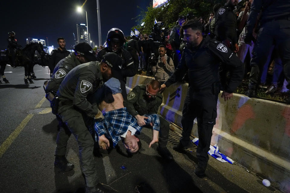 Israeli police officers disperse demonstrators blocking a highway during a protest against plans by Prime Minister Benjamin Netanyahu's government to overhaul the judicial system in Tel Aviv, Saturday, April 15, 2023. (AP Photo/Ariel Schalit)