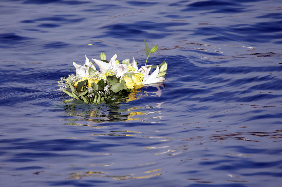 Flowers from relatives of the victims of the Costa Concordia shipwreck float in the water off the coast of the Tuscan Island of Giglio, Italy, Monday, Jan. 13, 2014. Survivors of the capsized Costa Concordia are commemorating the second anniversary of the grounding off Tuscany that killed 32 people with a candlelight march on the island later on and a moment of silence in the Italian courtroom where the captain is on trial. (AP Photo/Gregorio Borgia)