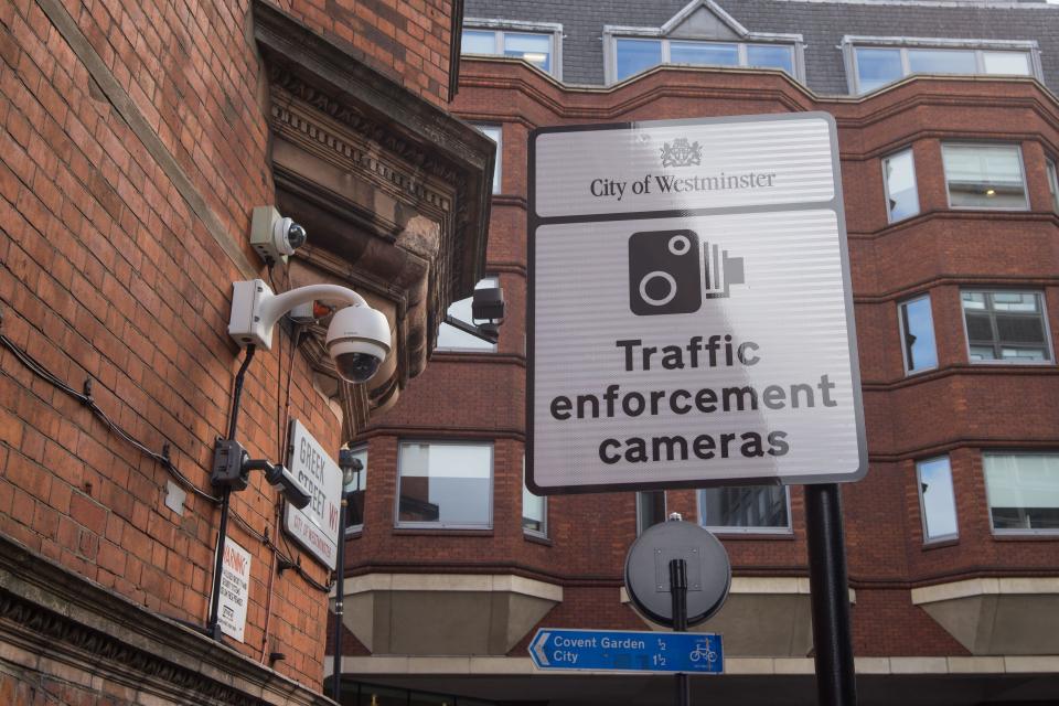 Traffic enforcement sign with CCTV cameras hanging off a brick wall. London