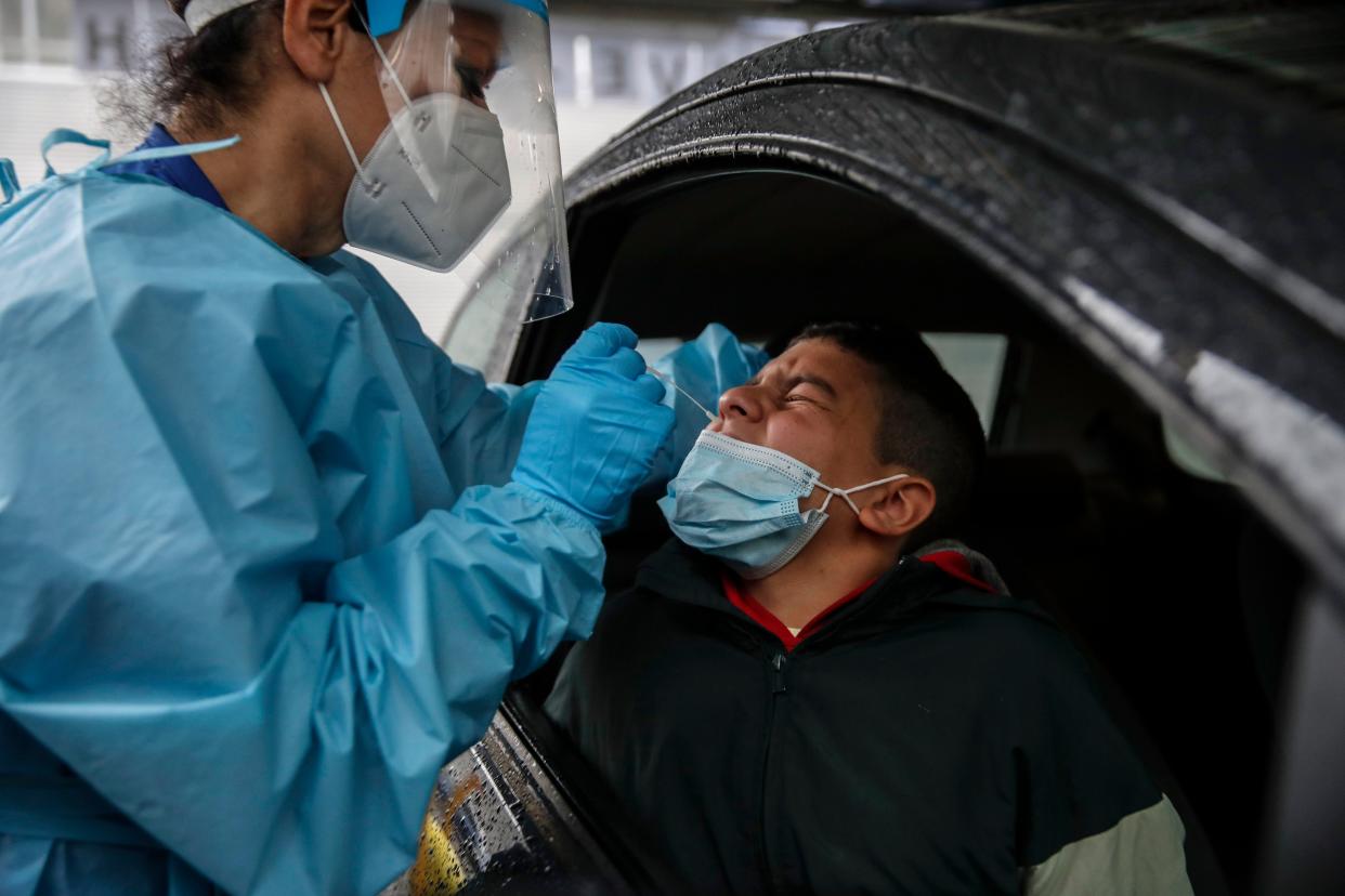 Medical staff takes a swab as she tests a boy for COVID-19 at a drive-through at the San Paolo hospital in Milan, Italy on Thursday, Oct. 15, 2020. Coronavirus infections are surging again in the region of northern Italy where the pandemic first took hold in Europe, renewing pressure on hospitals and health care workers.