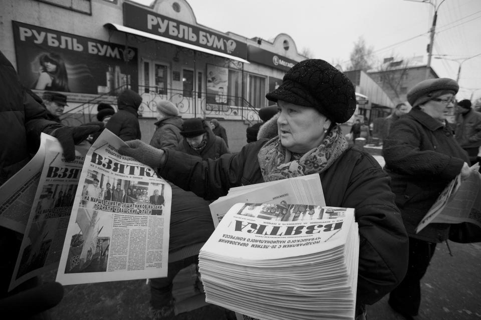 In this Nov. 14, 2012, photo, a woman hands out copies of the news paper Bribe in Cheboksary, the capital city of Chuvashia, Russia. Eduard Mochalov has found a new lease on life as a crusading journalist investigating corruption in his native region, fueled by tips from disgruntled businessmen and government workers. Undeterred by a system where the law is selectively used to protect the powerful and crack down on critics, Mochalov has quickly earned cult status _ not to mention the ire of countless local officials _ throughout the small province of Chuvashia. (AP Photo/Alexander Zemlianichenko)