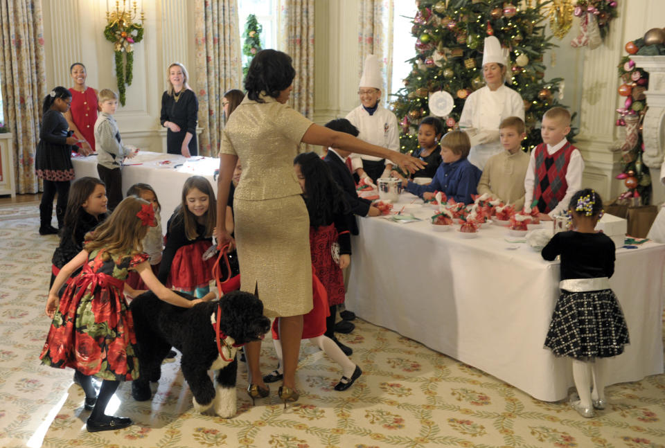 School children pet Obama family dog Bo, as First lady Michelle Obama looks at the holiday crafts the children were creating during a visit to the State Dining Room in the White House in Washington, Wednesday, Nov. 28, 2012. The crafts were part of the preview of the holiday decorations at the White House. The theme for the White House Christmas 2012 is Joy to All. School children were also in the State Dining Room decorating holiday treats. (AP Photo/Susan Walsh)
