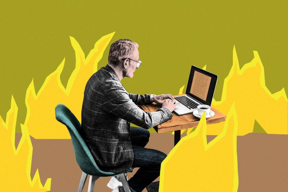 A man sits calmly typing on a laptop amid the flames from the "This is Fine" meme.