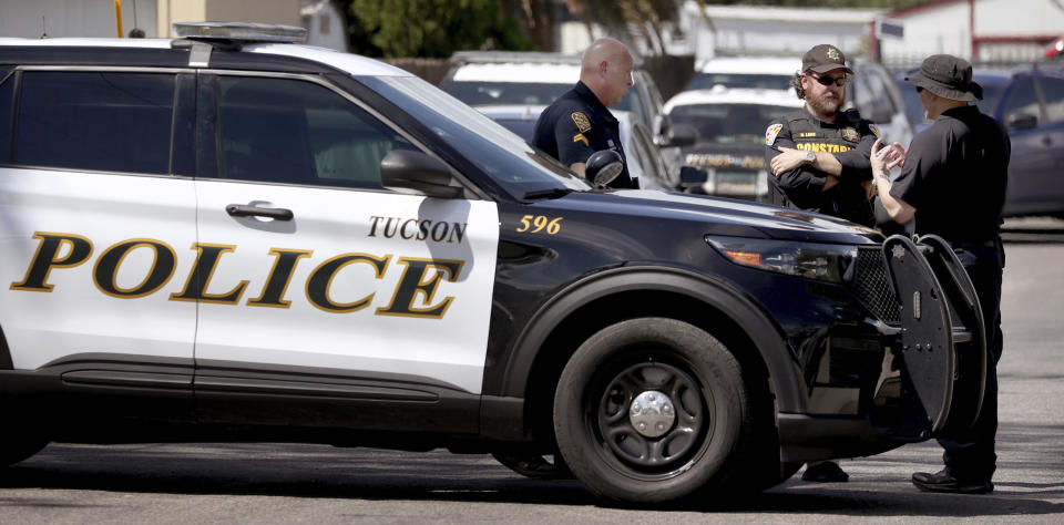 Tucson Police officers talk with a Pima County constable at a roadblock on Palo Verde Ave. just south of Lind Road and the shooting scene at Lind Commons Apartment in Tucson, Ariz., on Thursday, Aug. 27, 2022. A local constable was among four people fatally shot at the apartment complex while serving an eviction notice. Gov. Doug Ducey identified Pima County Constable Deborah Martinez-Garibay, 43, as one of the victims. (Kelly Presnell/Arizona Daily Star via AP)