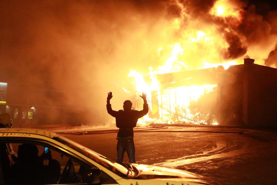 A protestor poses for a &quot;hands up&quot; photo in front of a burning building on West Florissant Ave. in Ferguson, Mo., Monday, Nov. 24, 2014. (AP Photo/St. Louis Post-Dispatch, Christian Gooden) Click for slideshow
