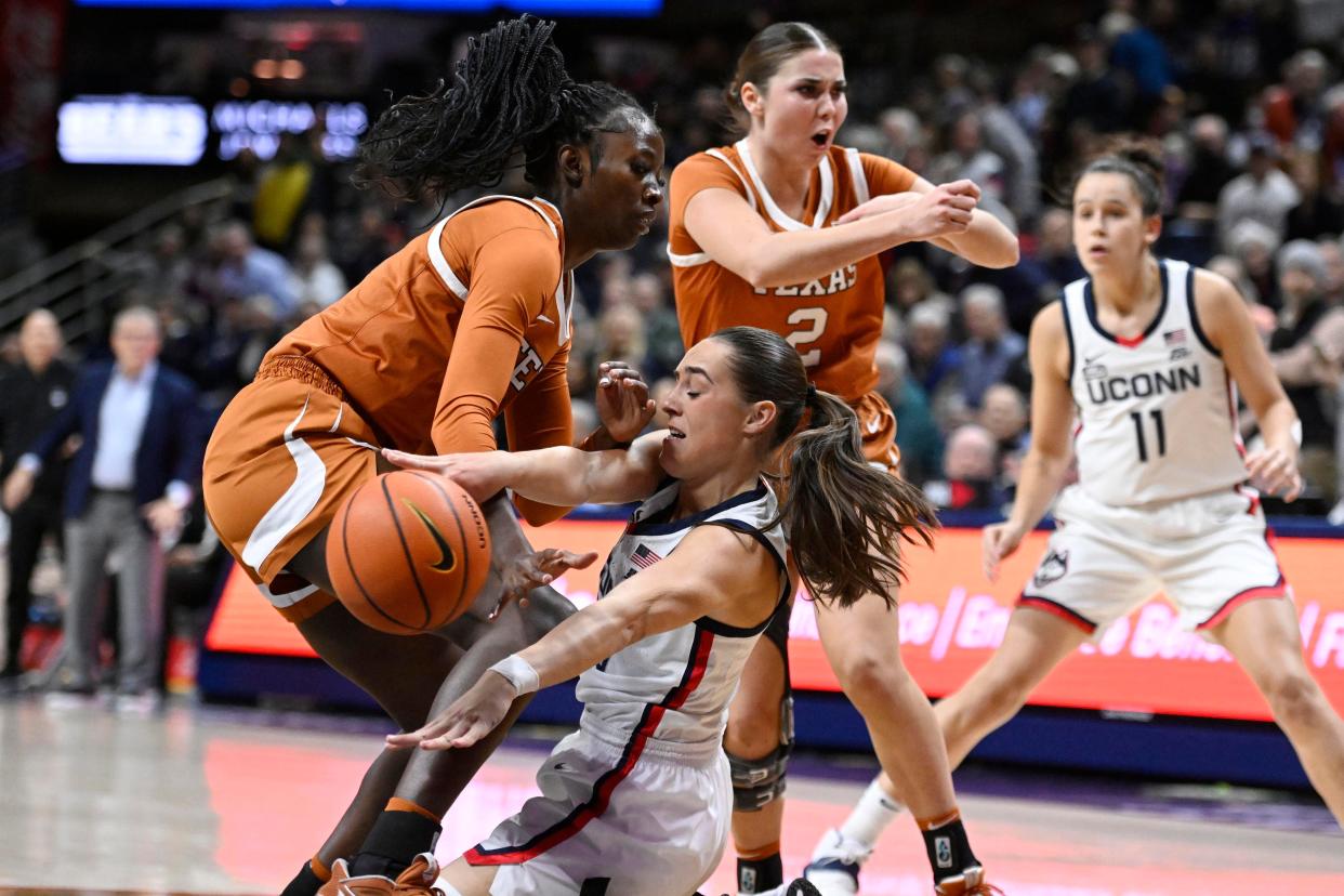 Connecticut's Nika Muhl, center, passes under pressure from Texas' Amina Muhammad, left, during a game last year in Storrs, Conn.