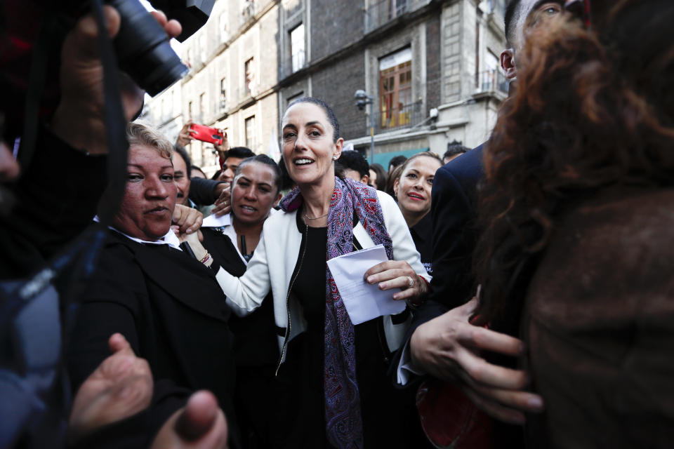 Mexico City's newly sworn-in mayor Claudia Sheinbaum greets people as she walks to an event in Mexico City, Wednesday, Dec. 5, 2018. The key promises of Sheinbaum, Mexico City's first elected female mayor, include reducing crime and enforcing zoning laws, a hot-button issue in the constantly growing megalopolis where developers routinely build bigger buildings than zoning rules allow. (AP Photo/Eduardo Verdugo)