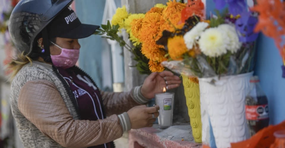 Mujer poniendo flores en panteón