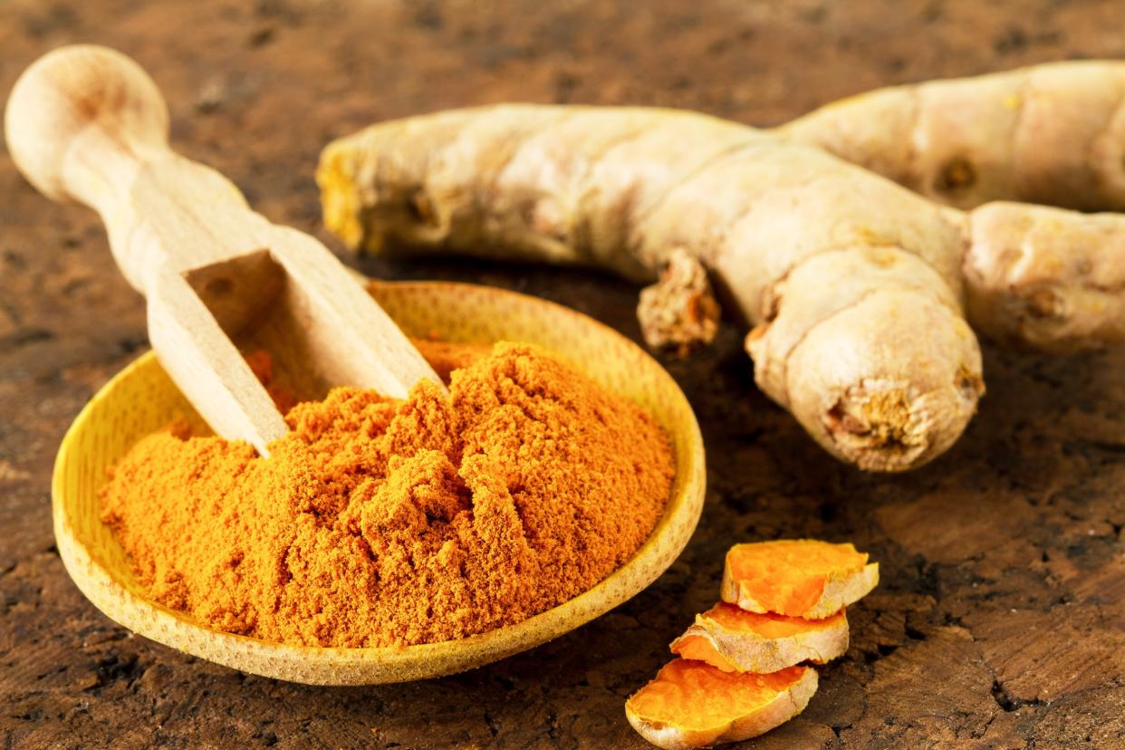 turmeric root and turmeric powder on wooden background