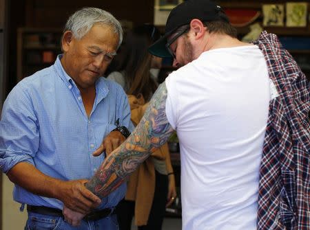 Farmer Tom Chino (L) looks at tattoos of vegetables on the arm of southern cuisine Chef Sean Brock as Brock visits the Chino family farm in Rancho Santa Fe, California November 16, 2014. REUTERS/Mike Blake