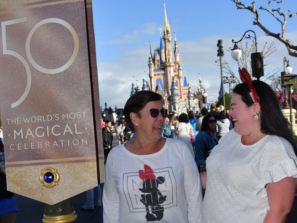 megan and her mom posing with a 50th anniversary banner at magic kingdom