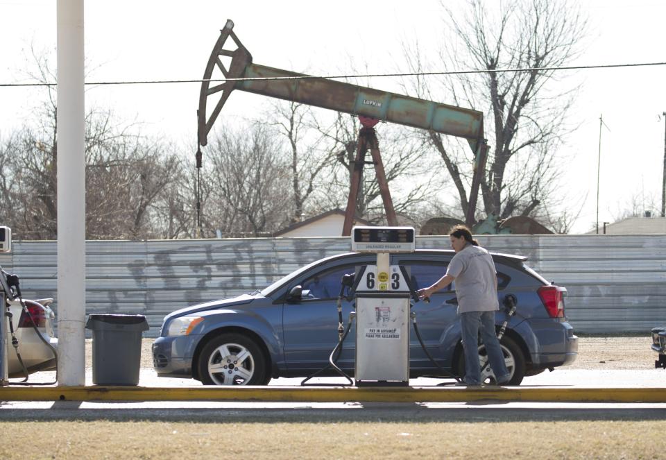 A motorist fills their car with gas at a gas station near an oil field pumping rig in Oklahoma City.