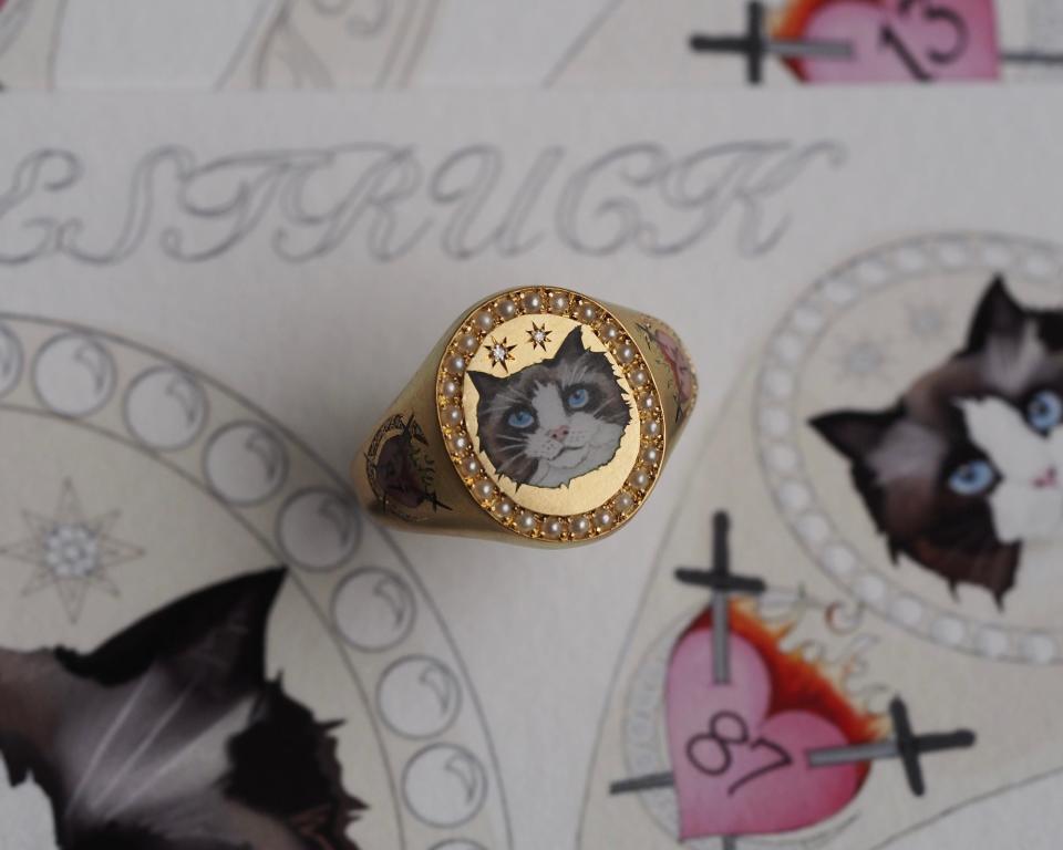 A gold ring with a portrait of a cat on it.