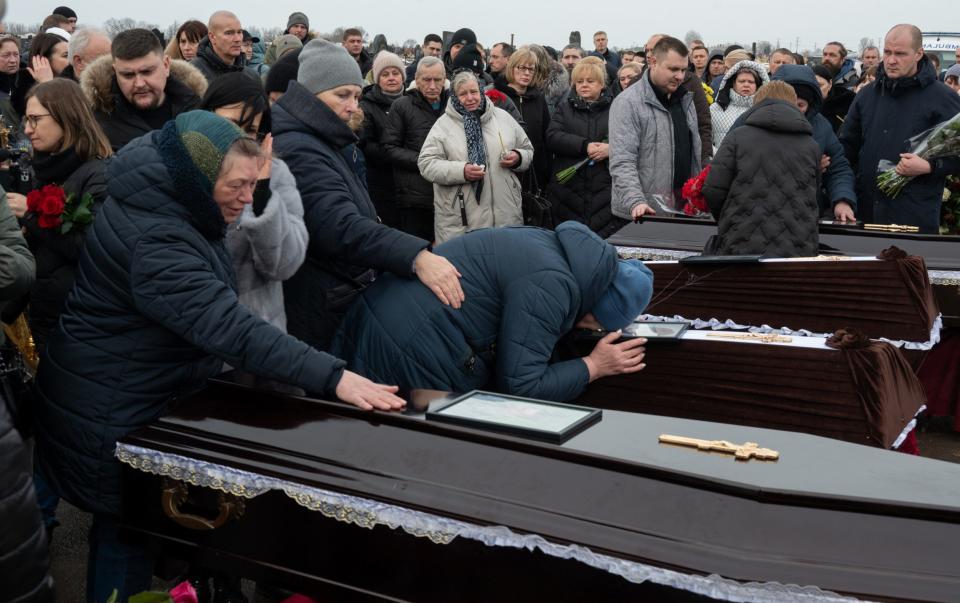 People mourn as they attend the burial of seven-year-old Alyosha in Kharkiv