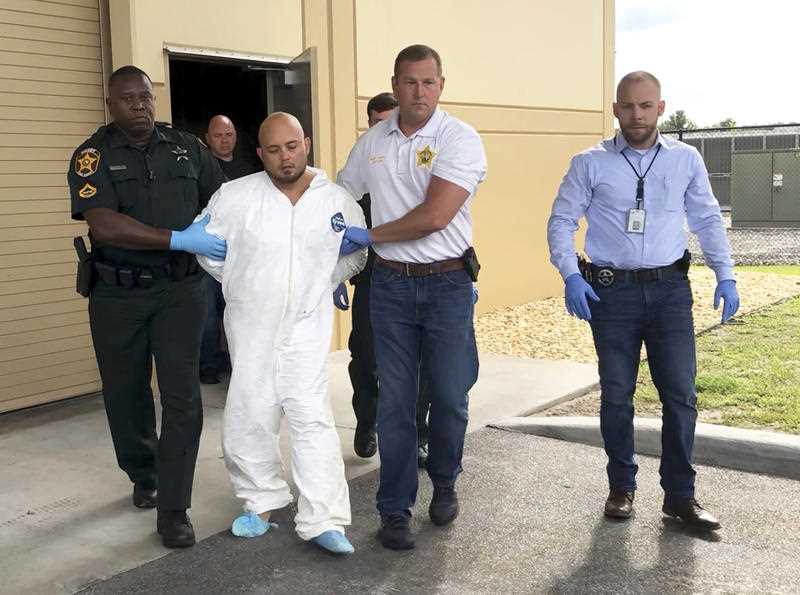 Quadruple murder suspect Bryan Riley is led from the Polk County Sheriff’s Office in Lakeland, Florida.