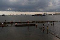 Youth play on a wall surrounded by rising water during high tide at Muara Baru port in Jakarta, Indonesia, January 3, 2018. REUTERS/Beawiharta