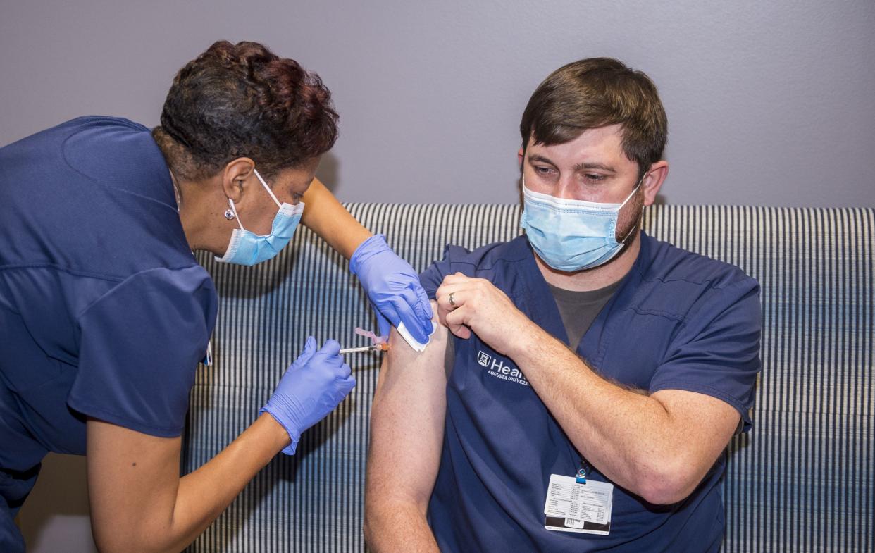 Registered nurse Amanda Wright, left, gives a shot of the Moderna COVID-19 vaccine to registered nurse Paul Smith at Augusta University in Augusta, Ga. on Wednesday morning, Dec. 30, 2020.