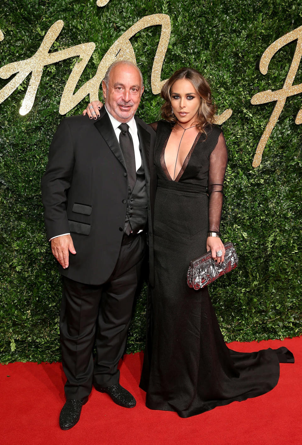 Philip Green and Chloe Green in a plunging black gown with sheer sleeves.