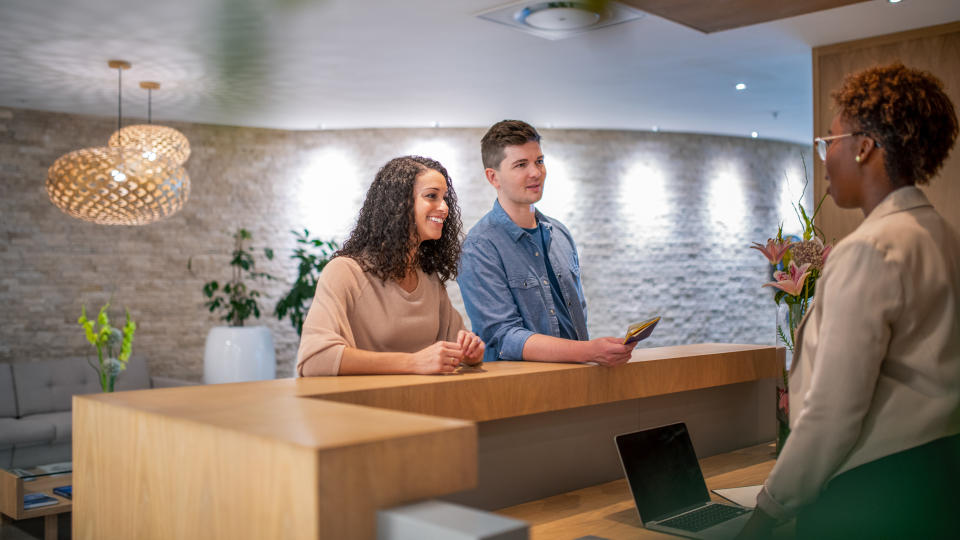 Mid adult couple discussing with female receptionist.