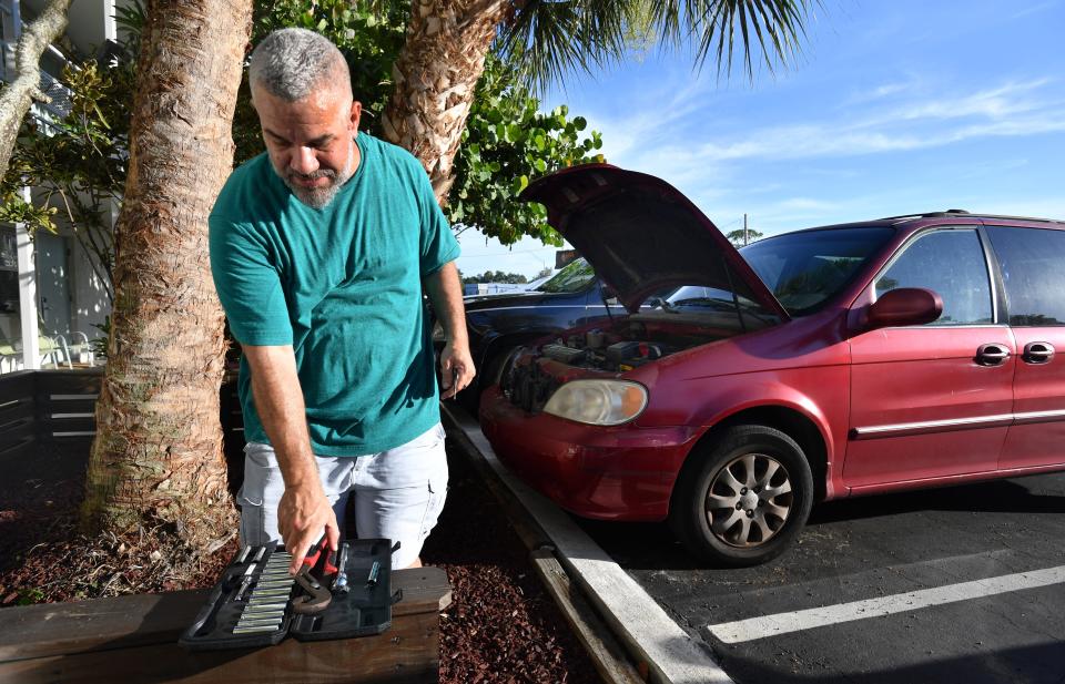 David Cabrera puts his tools away after fixing a loose battery connection on his family's 2003 Kia minivan in the parking lot of the Regency Inn in Sarasota.