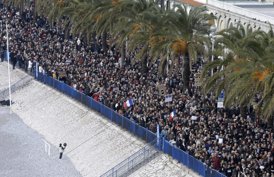A child holding a ball and standing on the beach of Nice, looks at a silent march for victims of the shooting at the satirical newspaper Charlie Hebdo, Saturday, Jan. 10, 2015, in Nice, southeastern France. Ten journalists and two policemen were killed on Jan. 7 in a terrorist attack at the Charlie Hebdo headquarters in Paris. (AP Photo/Lionel Cironneau)