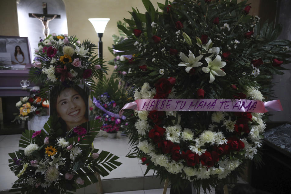 A portrait of slain woman Marbella Valdez is displayed next to a floral arrangement that reads in Spanish "Marbe, your mom loves you," next to her coffin during her wake at a funeral home in Tijuana, Mexico, Thursday, Feb. 13, 2020. When the law student’s body was found at a garbage dump in Tijuana, the man who was obsessed with her demanded police solve the case, attended her funeral, and a week later was arrested and charged with her murder. The man, identified by Mexican rules only by his first name, Juan, has insisted on his innocence. (AP Photo/Emilio Espejel)