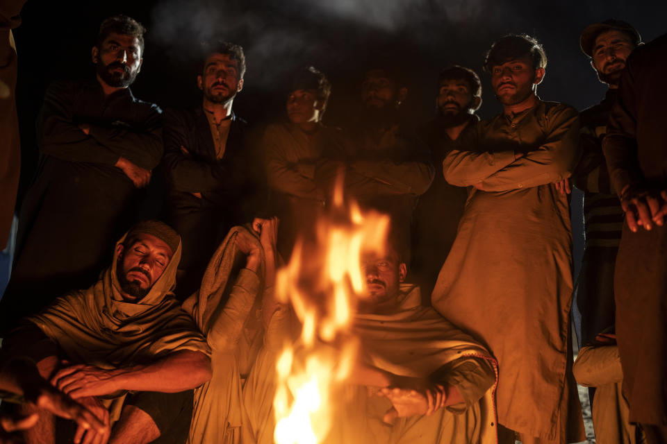 Afghan refugees warm themselves with fire in a camp near the Torkham Pakistan-Afghanistan border, in Torkham, Afghanistan, Saturday, Nov. 4, 2023. A huge number of Afghans refugees entered the Torkham border to return home hours before the expiration of a Pakistani government deadline for those who are in the country illegally to leave or face deportation. (AP Photo/Ebrahim Noroozi)