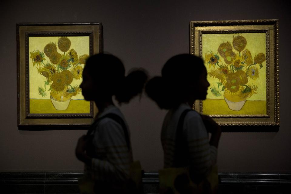 Identical twins Ella, left, and Eva, aged 12, pose for photographers in front of two versions of Dutch-born painter Vincent van Gogh's "Sunflowers", the left one from 1888 and the right one from 1889, during a photocall at the National Portrait Gallery in London, Friday, Jan. 24, 2014. The two paintings are being reunited in London for the first time in 65 years, with the 1889 version on loan from the Van Gogh Museum in Amsterdam. They will be displayed together until April 27. (AP Photo/Matt Dunham)