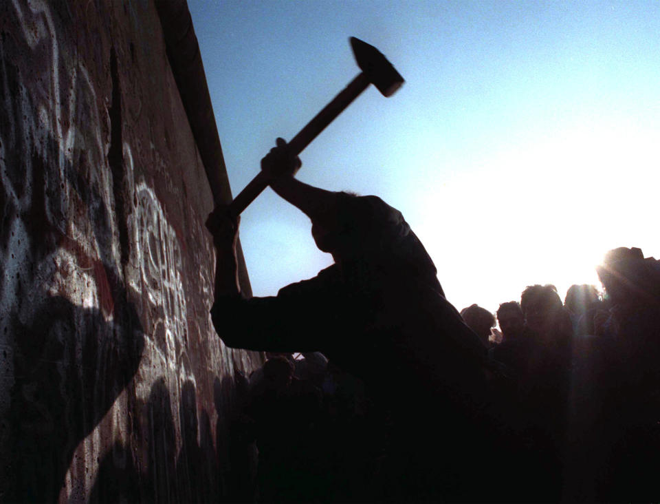 FILE - A man hammers away at the Berlin Wall on Nov. 12, 1989 as the border barrier between East and West Germany was torn down after 28 years, symbolically ending the Cold War. Former award-winning Associated Press photographer John Gaps III, who documented everything from war zones to the NCAA College World Series during his career, was found dead at his home Monday, Oct. 17, 2022, in Des Moines, Iowa, his family confirmed Tuesday. He was 63. (AP Photo/John Gaps III)