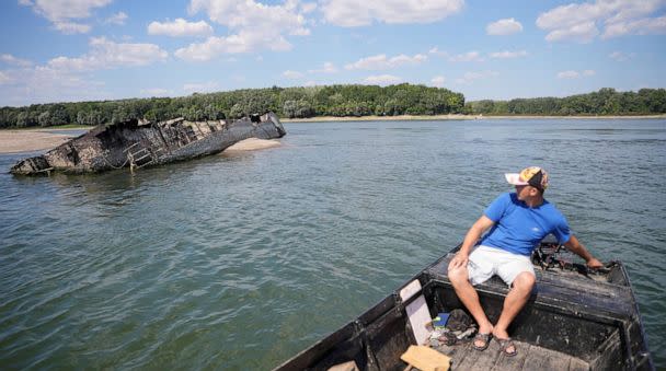 PHOTO: Local fisherman Ivica Skodric, sails on his boat past the wreckage of a World War II German warship in the Danube in Prahovo, Serbia August 18, 2022. (Fedja Grulovic/Reuters)