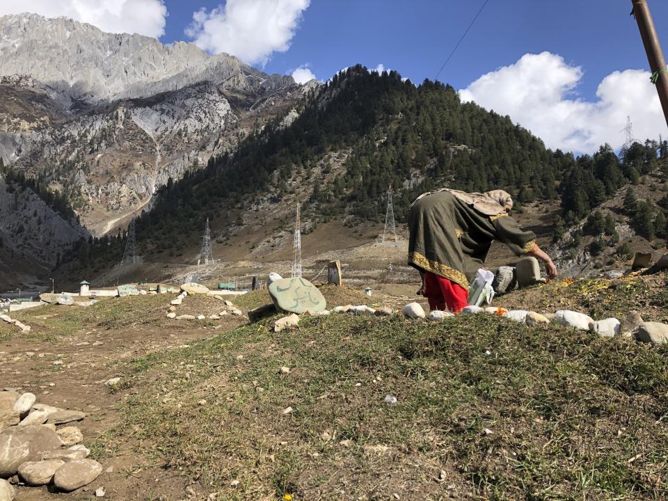 A woman offers flowers as relatives of suspected rebels killed by government forces visit a graveyard in Sonamarg, a remote mountainous resort in Indian controlled Kashmir, Nov.3, 2020. The picturesque tourist spot where a small hill meant for the bodies of rebels started small in April has since nearly filled up. Indian authorities in a new controversial policy in 2020 started to consign blood-soaked bodies of scores of Kashmiri rebels to unmarked graves, denying the mourning families a proper funeral and a burial at their own ancestral home graveyards. (AP Photo/Aijaz Hussain)