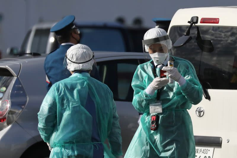 Health officials dressed in protective gear are seen near the cruise ship Diamond Princess at Daikoku Pier Cruise Terminal in Yokohama