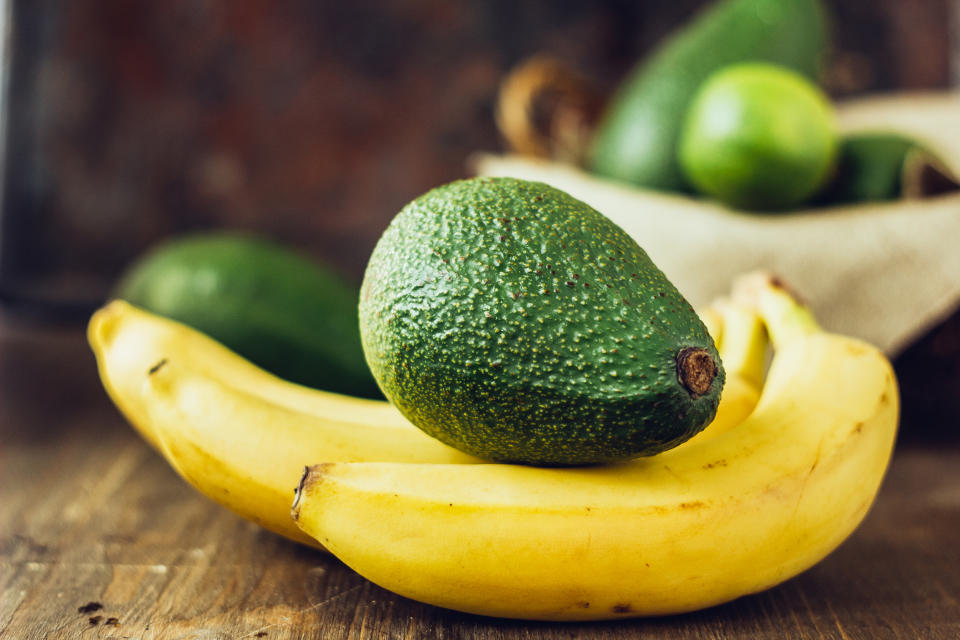 Avocado and banana over brown wooden background. (Getty Images)