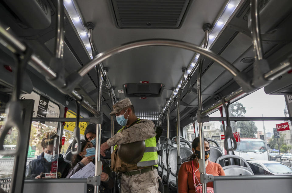 Un soldado verifica permisos de movilidad en un bus de pasajeros en Santiago, Chile, el jueves 25 de marzo de 2021. Las autoridades anunciaron el restablecimiento de una cuarentena en toda la ciudad para ayudar a contener la propagación del COVID-19. (AP Foto/Esteban Felix)