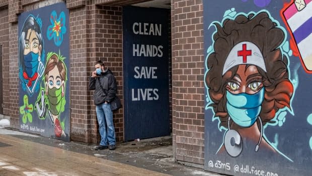 A man wearing a mask stands next to a mural in downtown Ottawa on March 1, 2021, during the COVID-19 pandemic. (Brian Morris/CBC - image credit)