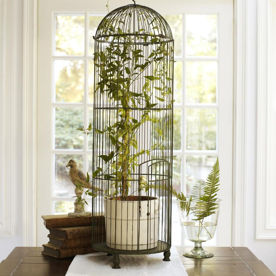 In this photo provided by Pottery Barn, this tall wire birdcage in a distressed green painted wire, can be filled with a tall plant or just used as a decorative tabletop accessory. Victorians were fond of birds in all iterations, from illustrations to textile motifs to aviaries large and small. Those drawn to 19th-century style may be happy to learn that vintage garden decor is a trend for spring and summer. (AP Photo/Pottery Barn)