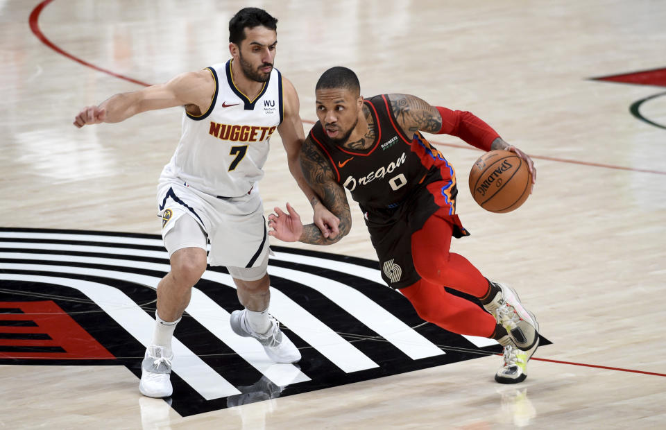 Portland Trail Blazers guard Damian Lillard, right, drives to the basket on Denver Nuggets guard Facundo Campazzo, left, during the first half of an NBA basketball game in Portland, Ore., Sunday, May 16, 2021. (AP Photo/Steve Dykes)
