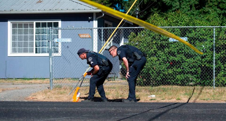 Officers from the Pierce County Sheriff's Department scan Ainsworth Ave.  S. on tire tracks to mark as evidence on the roadway on Saturday, July 24, 2021. Detectives are investigating a homicide after a man deliberately ran over another man in Parkland.