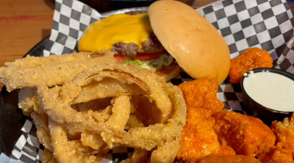 One of Blue’s Big Plates, the burger and wing platter at Blue Moose Burgers & Wings consists of a Moose's All-American cheeseburger served with four jumbo wings, shown here with a side of onion rings.