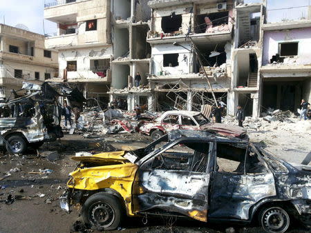 People inspect the site of a two bomb blasts in the government-controlled city of Homs, Syria, in this handout picture provided by SANA on February 21, 2016. REUTERS/SANA/Handout via Reuters