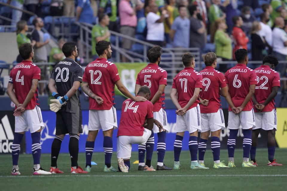 FC Dallas defender Nkosi Burgess (14) kneels during the singing of the national anthem before the team's MLS soccer match against the Seattle Sounders, Wednesday, Aug. 4, 2021, in Seattle. (AP Photo/Ted S. Warren)