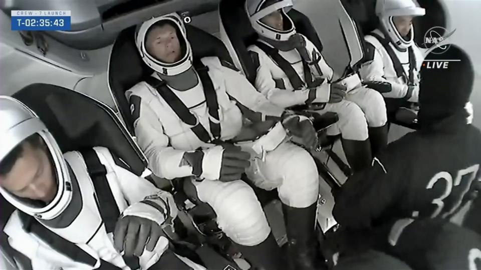 astronauts strap into a spaceship
