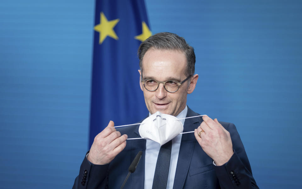 Heiko Maas, German Foreign Minister, puts on his mouth-nose protection at the end of the press conference on the informal virtual meeting of the foreign ministers of the member states of the Vienna nuclear agreement in Berlin, Germany, Monday, Dec. 21, 2020. (Kay Nietfeld/dpa via AP)