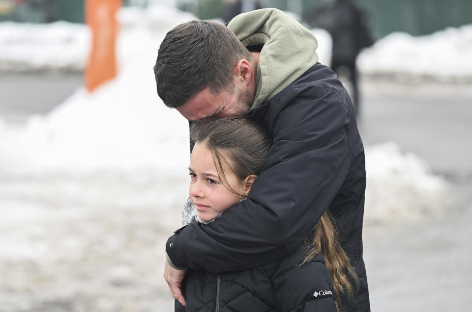 A man embraces a child at the site of a daycare centre in Laval, Quebec, on Thursday, Feb. 9, 2023, where a city bus crashed into the building killing two children. (Graham Hughes/The Canadian Press via AP)