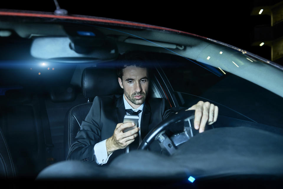 A file picture of a man in a suit using his mobile phone in his car.