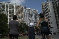 People watch firefighter Elielson Silva play his trumpet from the top of a ladder for residents cooped up at home, during a lockdown to help contain the spread of the new coronavirus in Rio de Janeiro, Brazil, Sunday, April 5, 2020. He draws cheers and enthusiastic clapping. “Hearing all that music restores our will to be in Rio, our sense of collectiveness,” Renata Versiani said from her windowsill, where she watched Silva play with her husband and young daughter. “Initiatives like this remind us of who we are as a community. It’s happiness to have a surprise like this.” (AP Photo/Leo Correa)